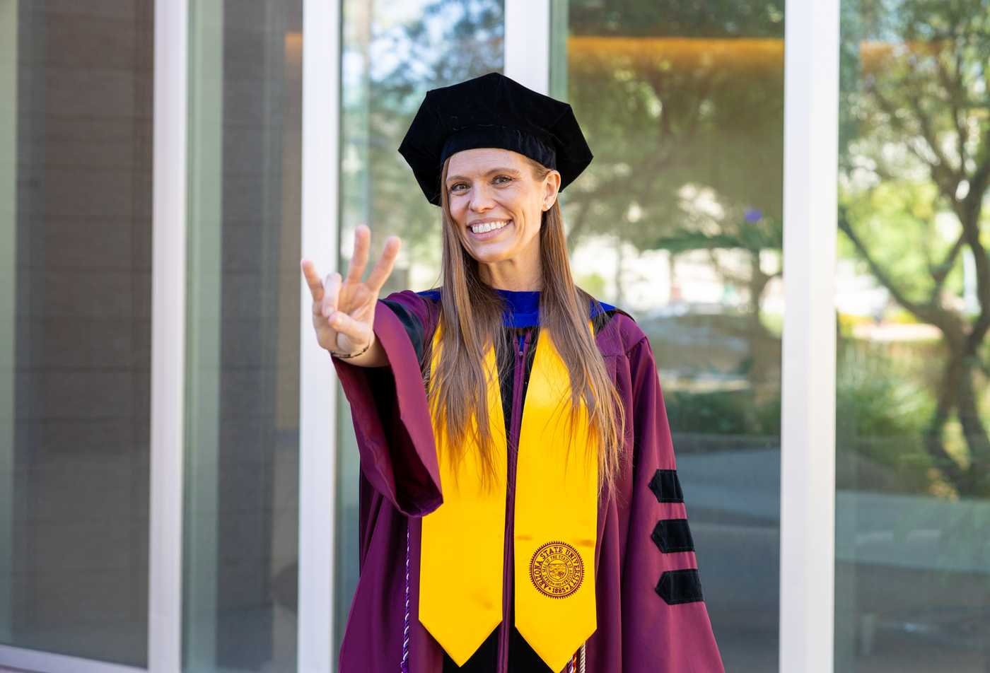 A PhD graduate in academic regalia symbolizes the expertise gained in the Nursing and Healthcare Innovation, PhD.