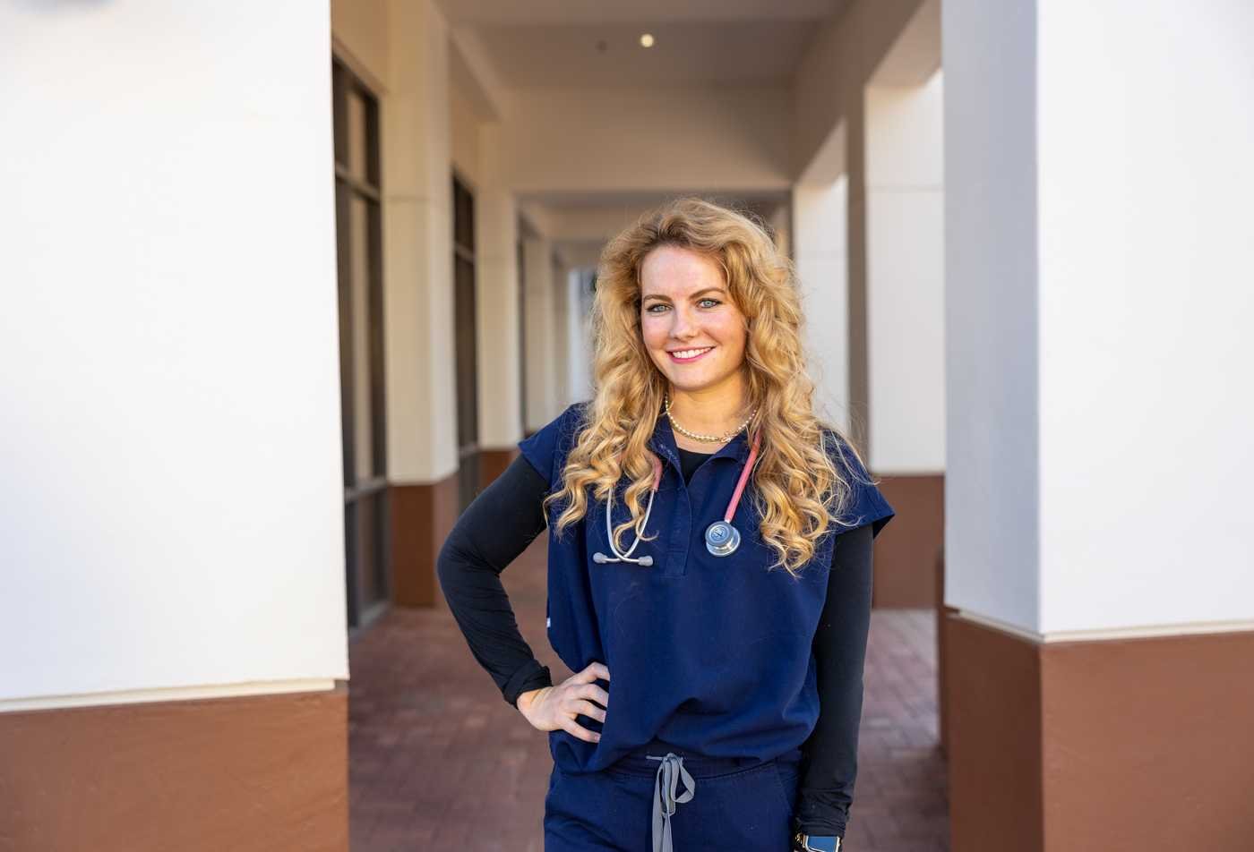 A nursing student poses in clinical attire with a stethoscope, symbolizing the expertise gained in the Nursing (Entry to Nursing Practice), MS.
