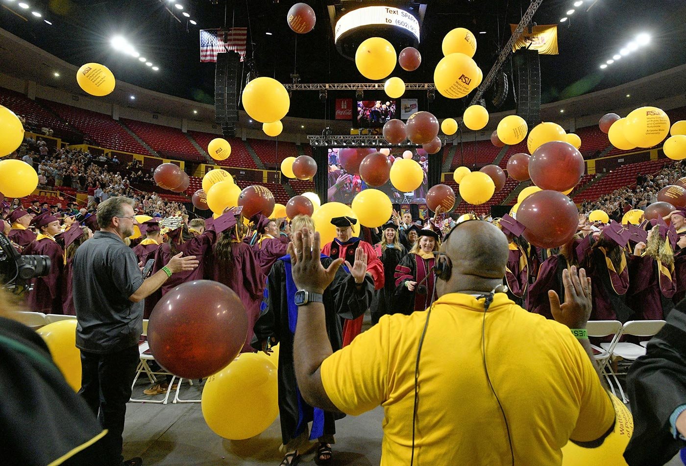 Graduates toss gold and brown balloons at commencement, capturing the festive energy taught in the Special Events Management minor.