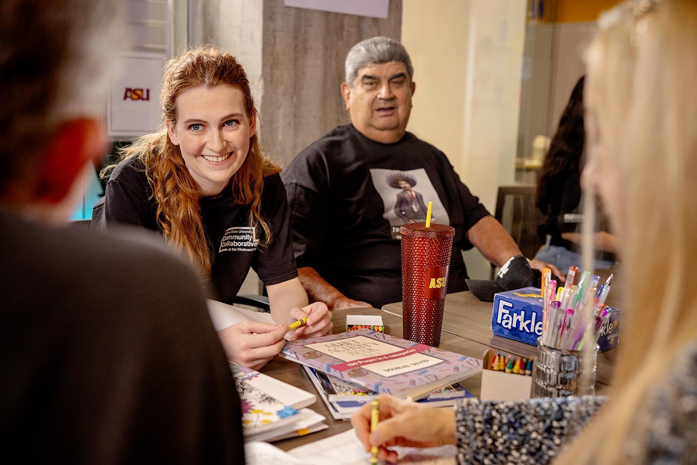 Students engage in a collaborative creative activity around a table, showcasing community involvement linked to ASU's Social Welfare minor.