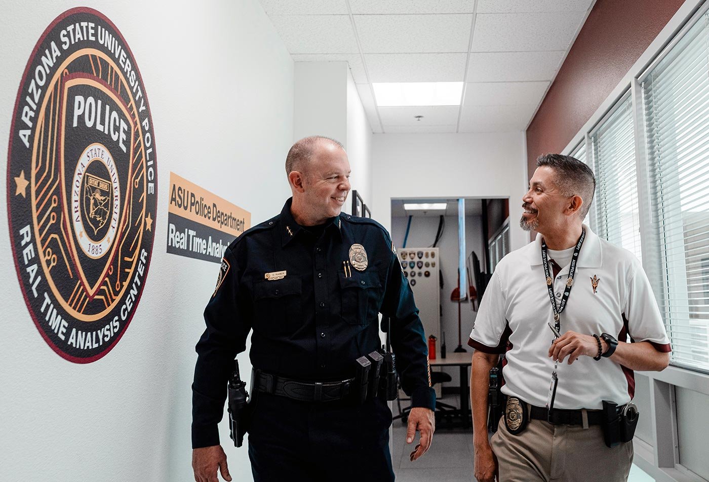 Two officers talk in a hallway at the ASU Police Department, reflecting the real-world ties within ASU's Criminal Justice degree.