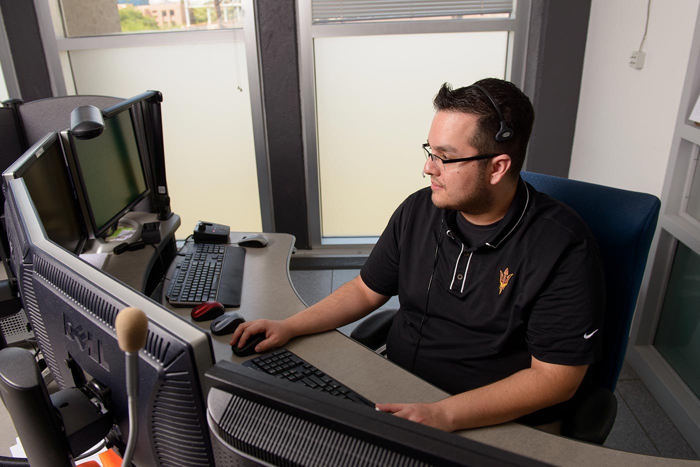 A student works at a multi-monitor workstation, reflecting the technical focus of this ASU cybersecurity concentration.
