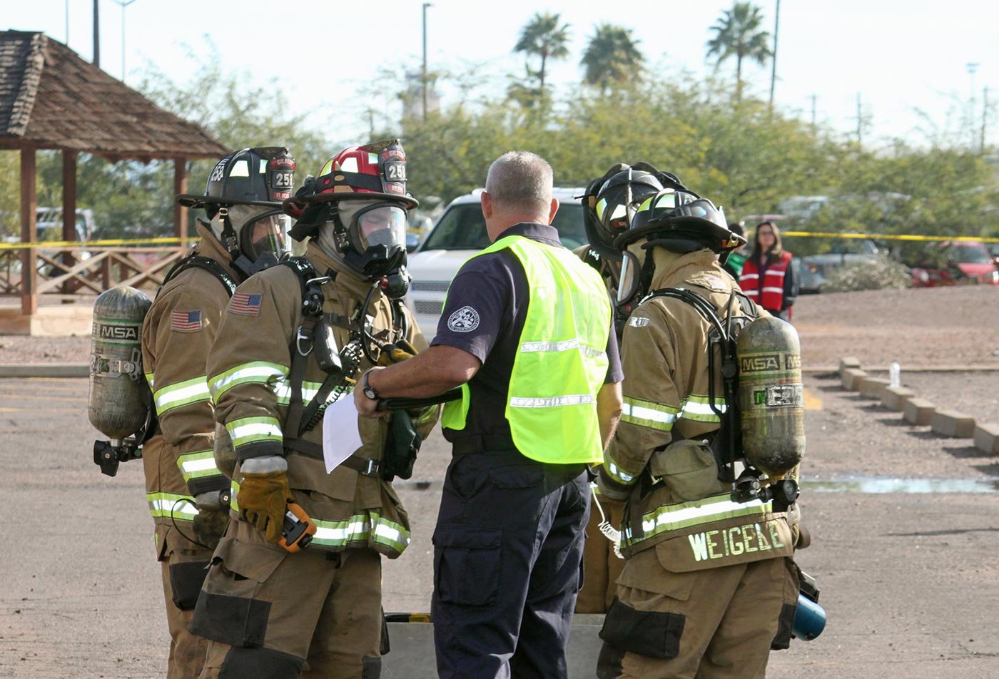 Firefighters in full gear talk with an instructor during training, mirroring the emergency scenarios studied in ASU's Emergency Management degree.