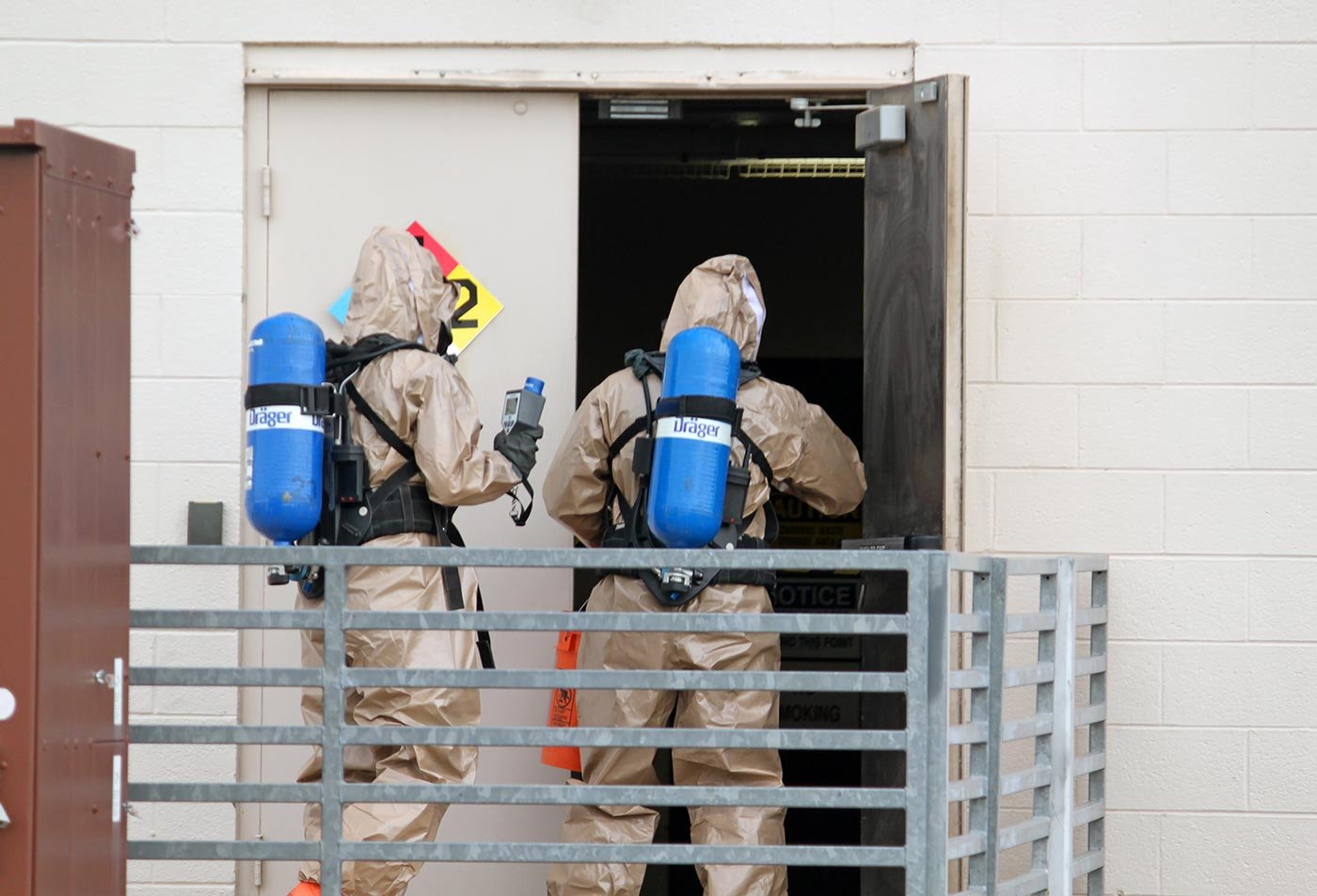 Individuals in protective suits enter a hazard-marked facility, reflecting the biosecurity focus of this ASU concentration.