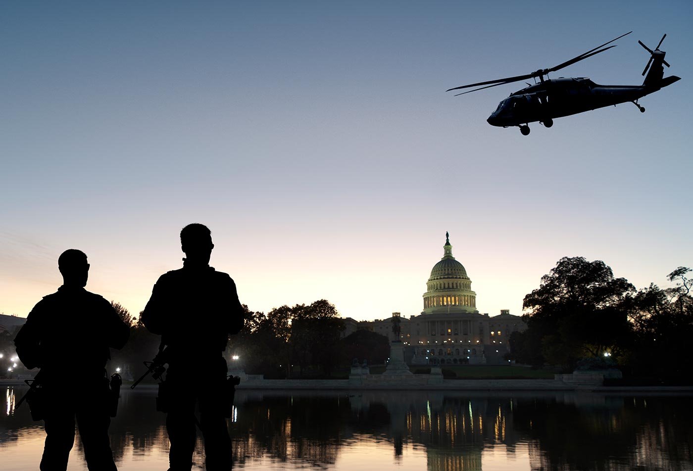 Silhouetted security personnel watch a helicopter near the U.S. Capitol, reflecting the stakes explored in this ASU concentration.