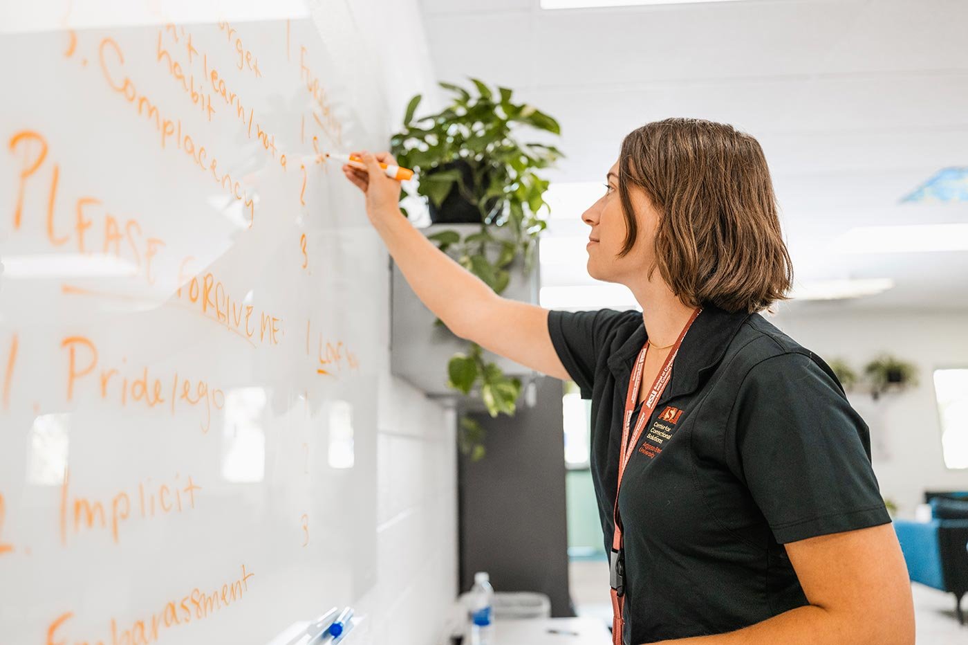 A student in a classroom writes on a whiteboard, illustrating practical skills in ASU's Law and Human Behavior program.