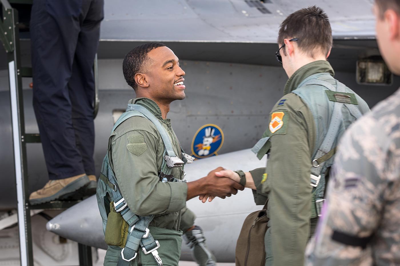 Students in flight suits shake hands near an aircraft, reflecting the field explored in this Public Policy concentration.