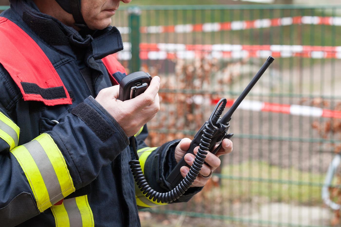 A firefighter holds a radio and phone, reflecting the real-time communication skills taught in ASU's Emergency Management concentration.