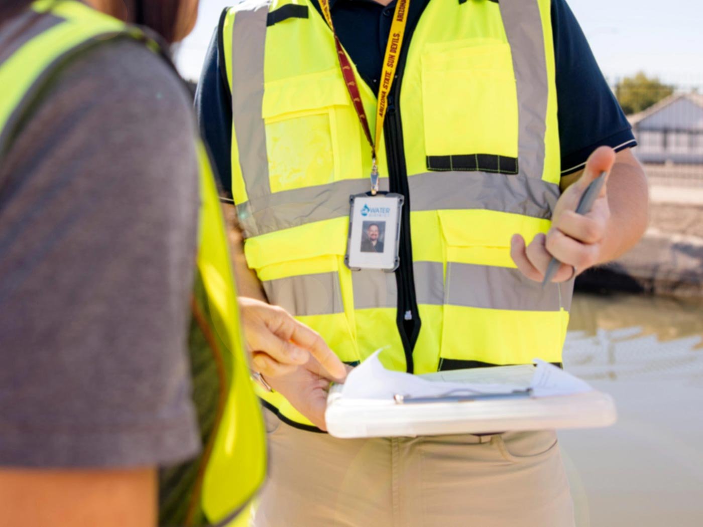 A person in a safety vest discusses plans with a colleague, reflecting the practical focus of ASU's Urban Management concentration.