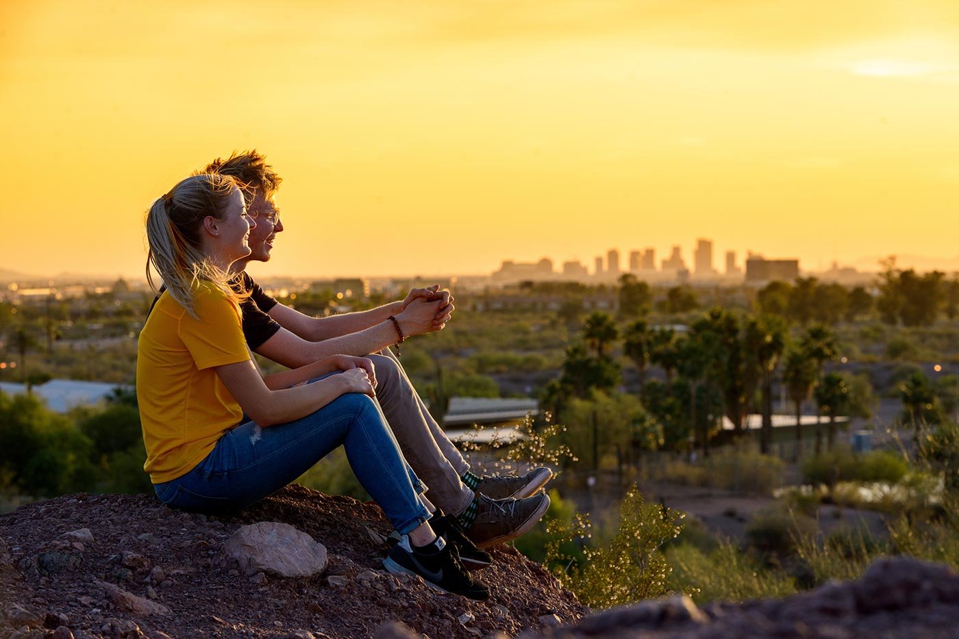 Two students share a quiet moment on a rocky outcrop at sunset, overlooking the landscape central to the Parks and Protected Area Management minor.