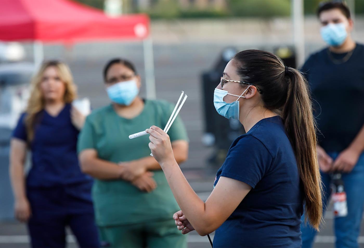 Students in scrubs and masks watch a peer demonstrate equipment, reflecting the collaborative training in this EMS concentration.