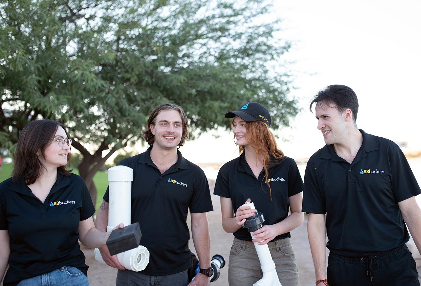 Students carry water sampling gear along a lakeshore, reflecting the fieldwork central to ASU's Environmental Policy concentration.