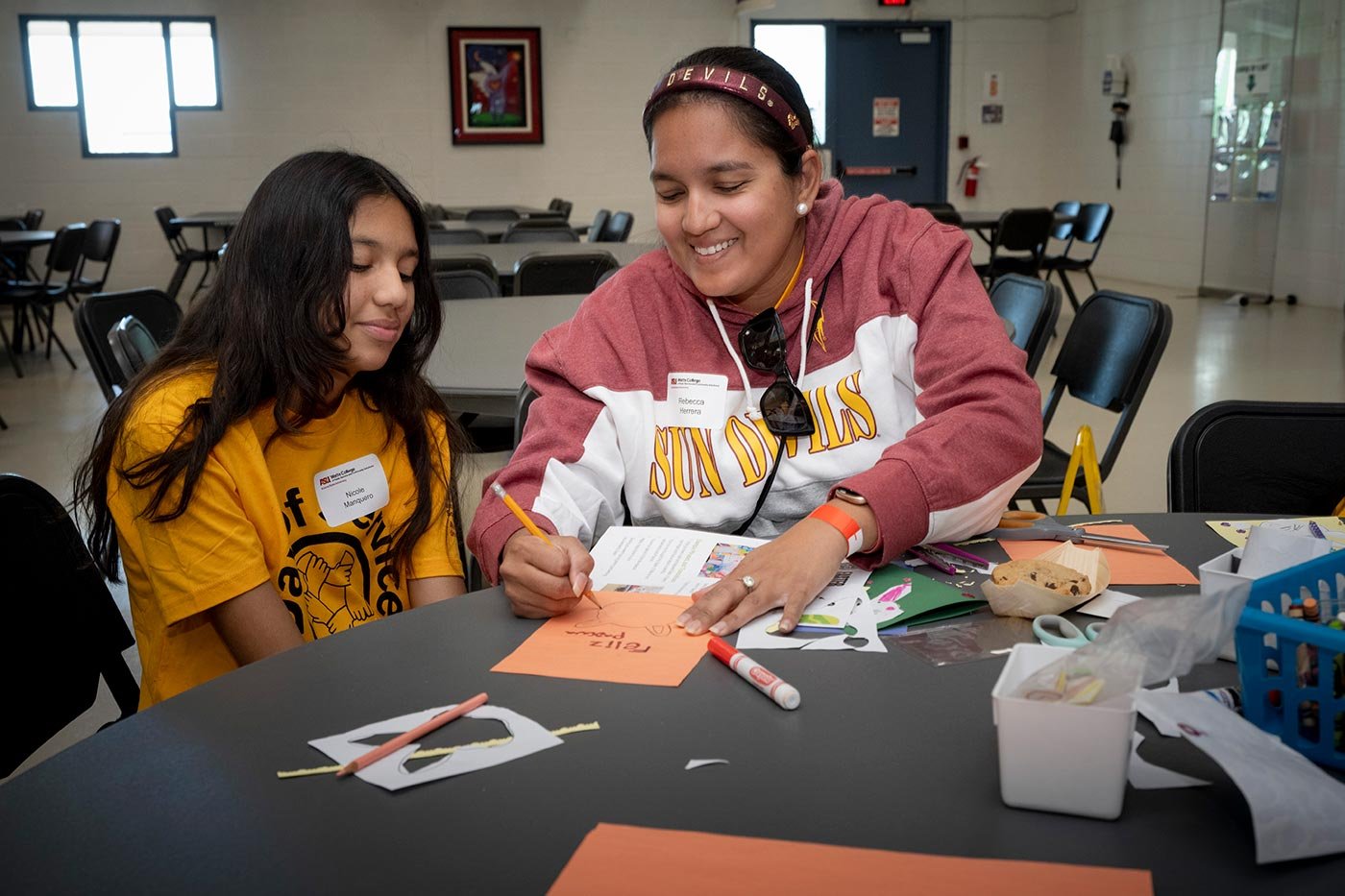 A woman in the MS in Community Resources and Development degree creates artwork while another student observes at a community-focused event.