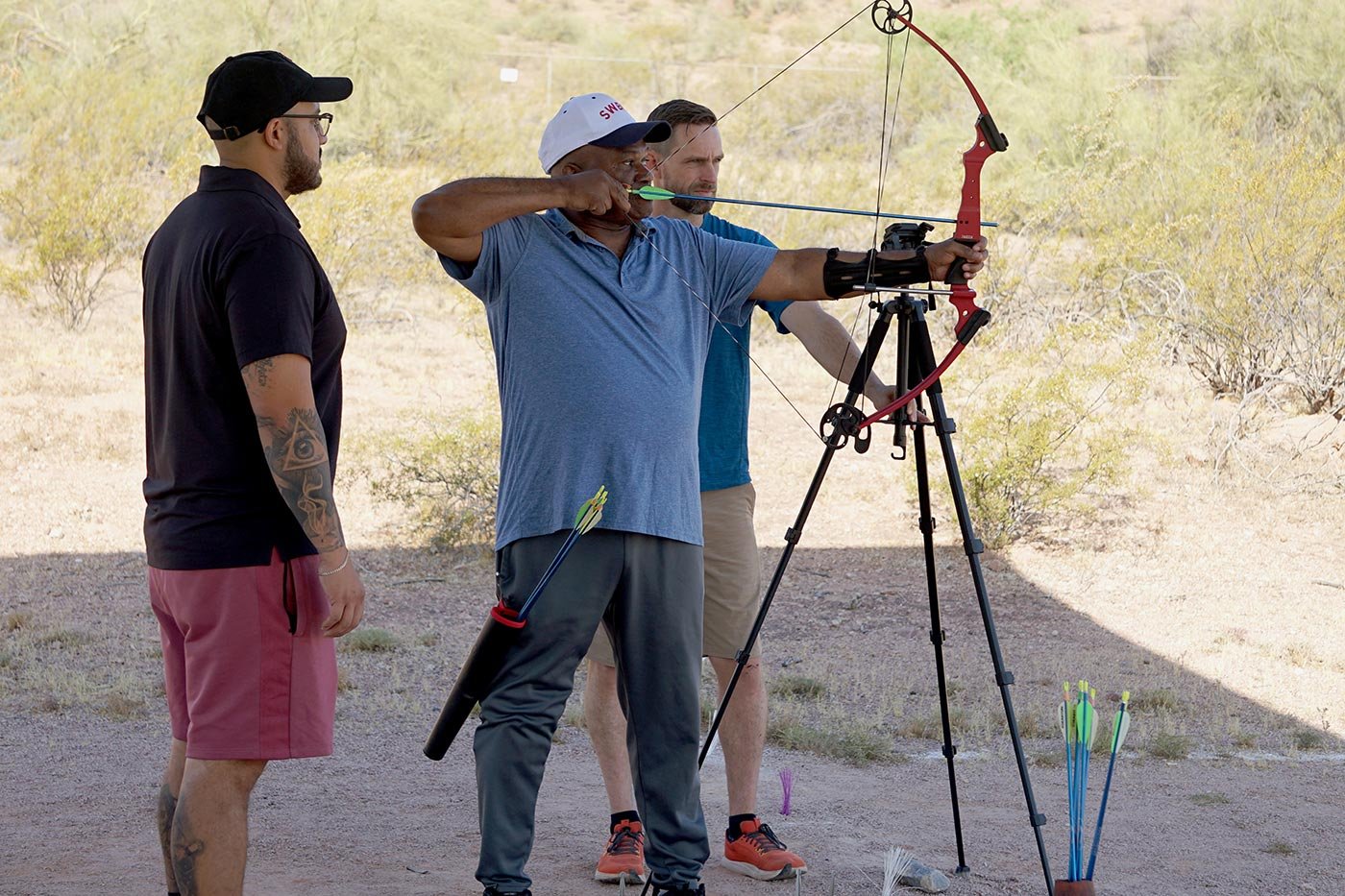 A person practices archery with support from two others at an outdoor range, showcasing skills built through ASU's Recreational Therapy degree.