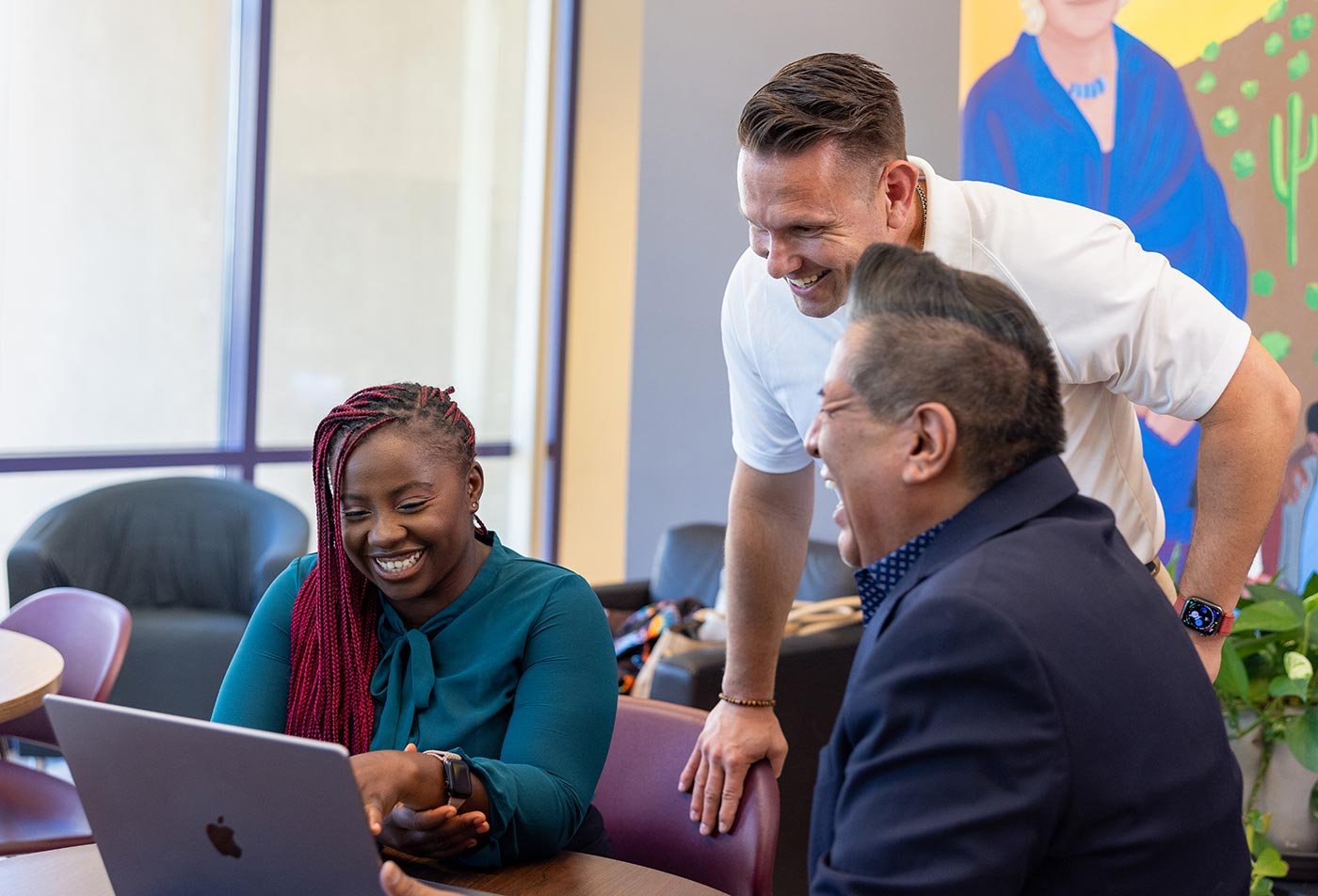 Students engage in discussion while examining a computer display, showcasing collaborative learning in ASU's PhD in Social Work program.