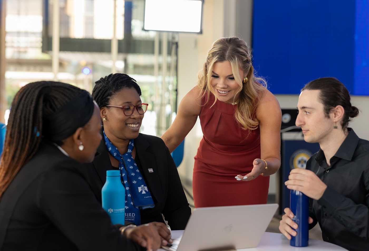 A diverse team meets around a laptop, showcasing cross-border collaboration in ASU's Global Management (Global Business), MGM program.