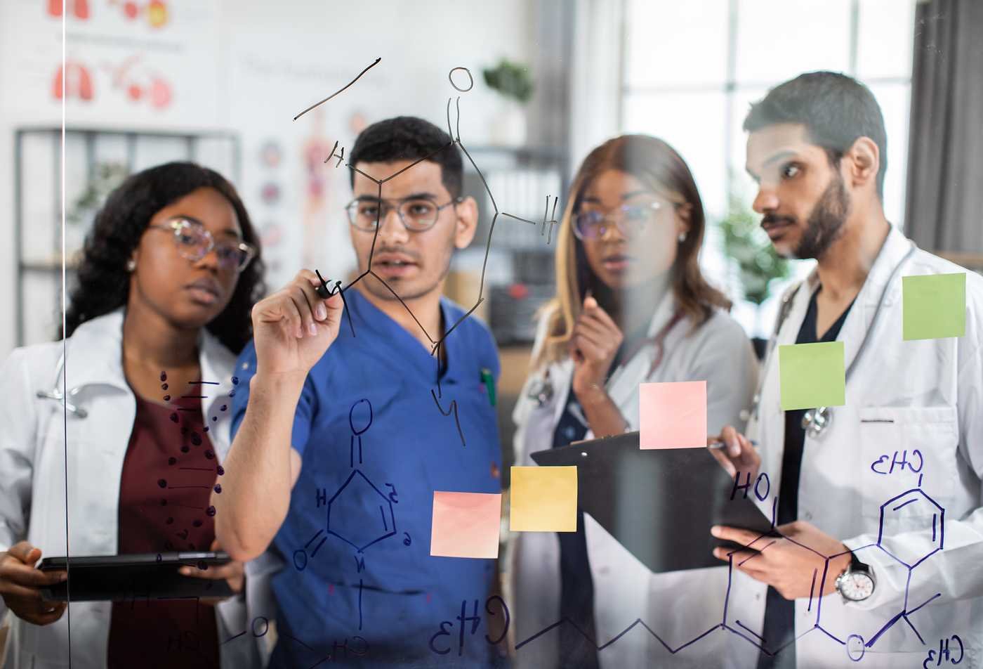 Researchers analyze chemical data on a glass board, representing innovation in ASU's Global Management (Global Health Care Innovation), MGM program.