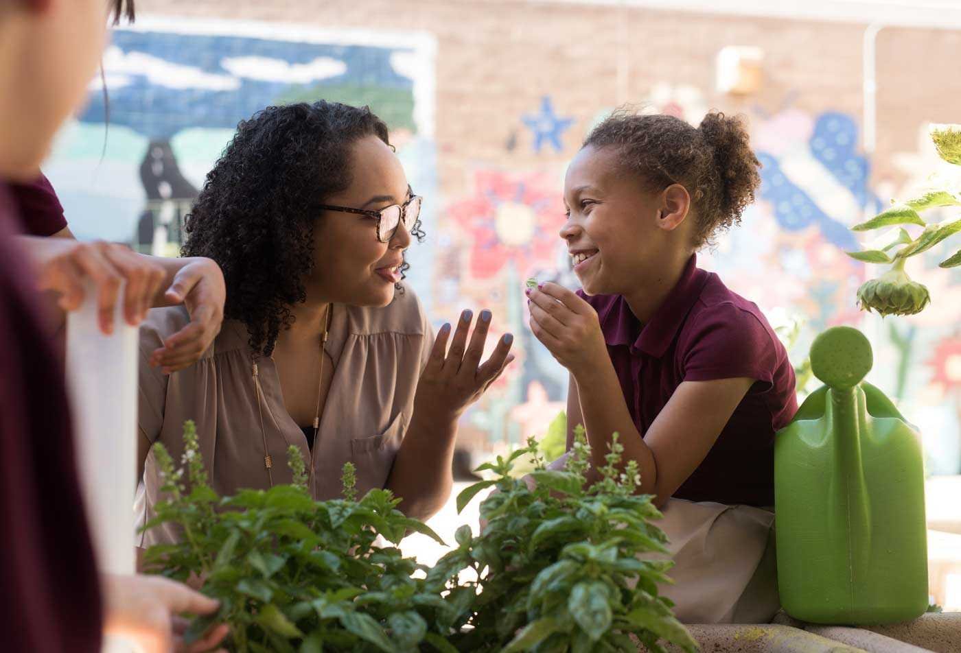 An instructor engages with a young student in a garden, showcasing the flexible education strategies explored in the BAE in Educational Studies.