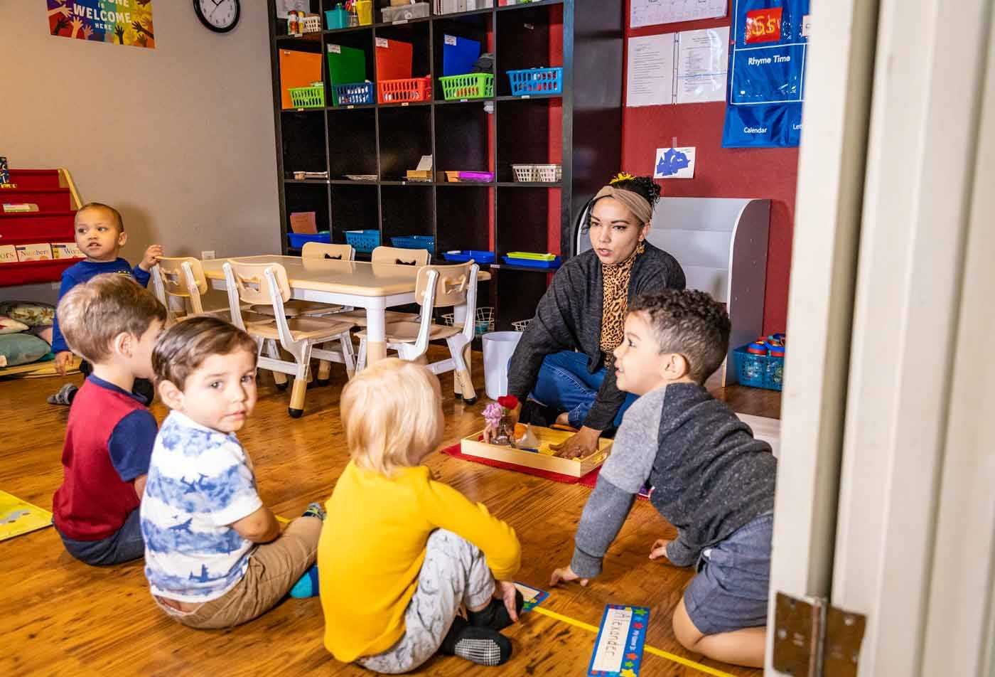 A teacher uses props with a group of toddlers sitting in a colorful classroom, showing the skills learned in the certificate in Early Childhood Education.