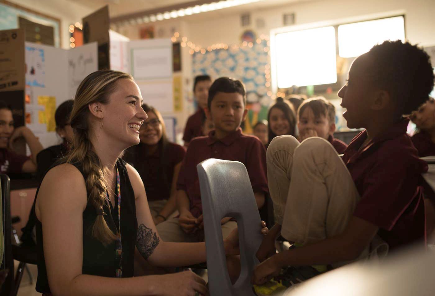 A young woman smiles at a boy in a classroom surrounded by attentive students, demonstrating the multicultural expertise gained in the BAE in Elementary Multilingual Education