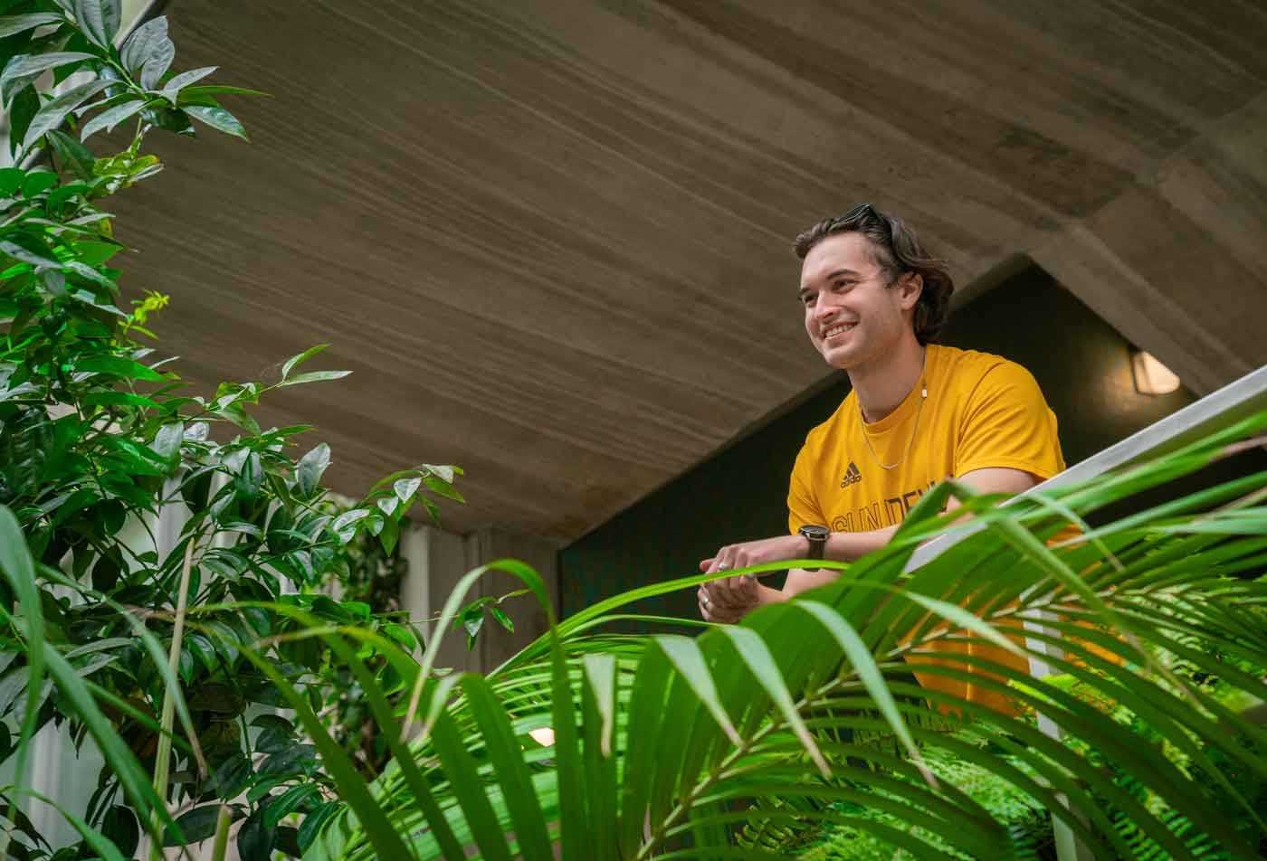 A smiling student looks out over plants, symbolizing the field of Environmental Education.