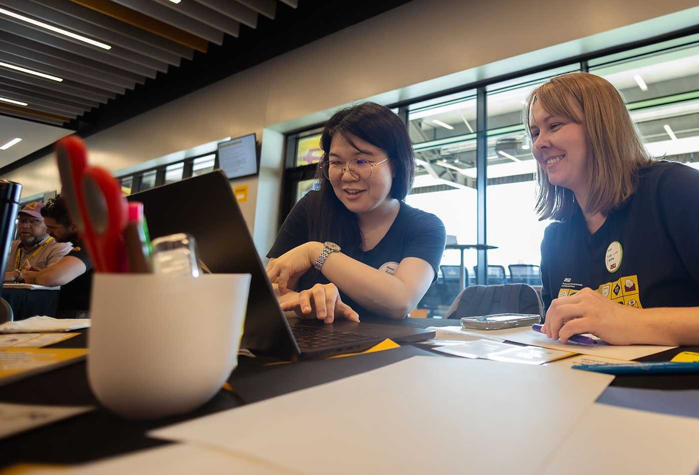 Students examine a laptop together, showcasing the collaborative learning environment in the MEd in Global Education.