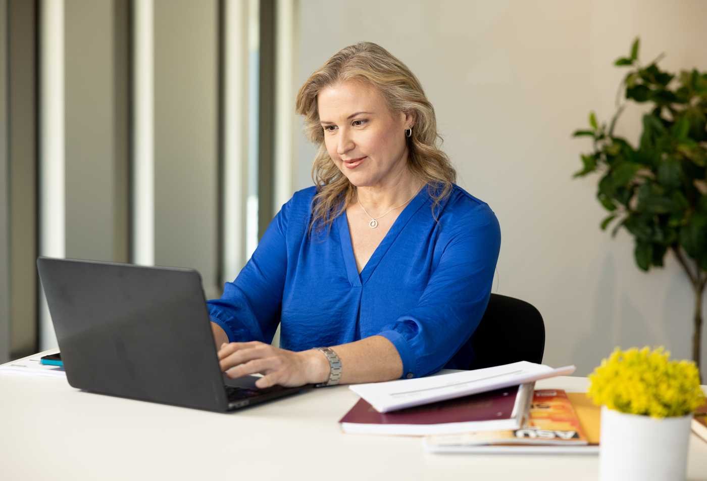 A professional interacts with a laptop, demonstrating the leadership skills gained in the EdD in Educational Leadership and Innovation (Policy/Admin).