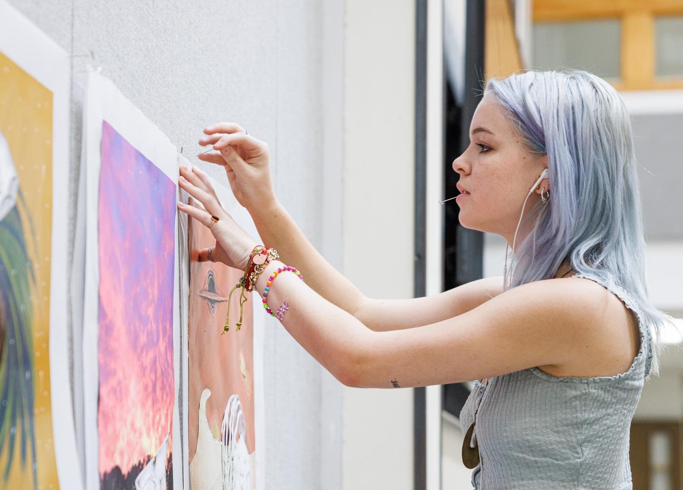 A student hangs art on a display, showcasing creativity in ASU's Exploratory Humanities, Fine Arts and Design degree.