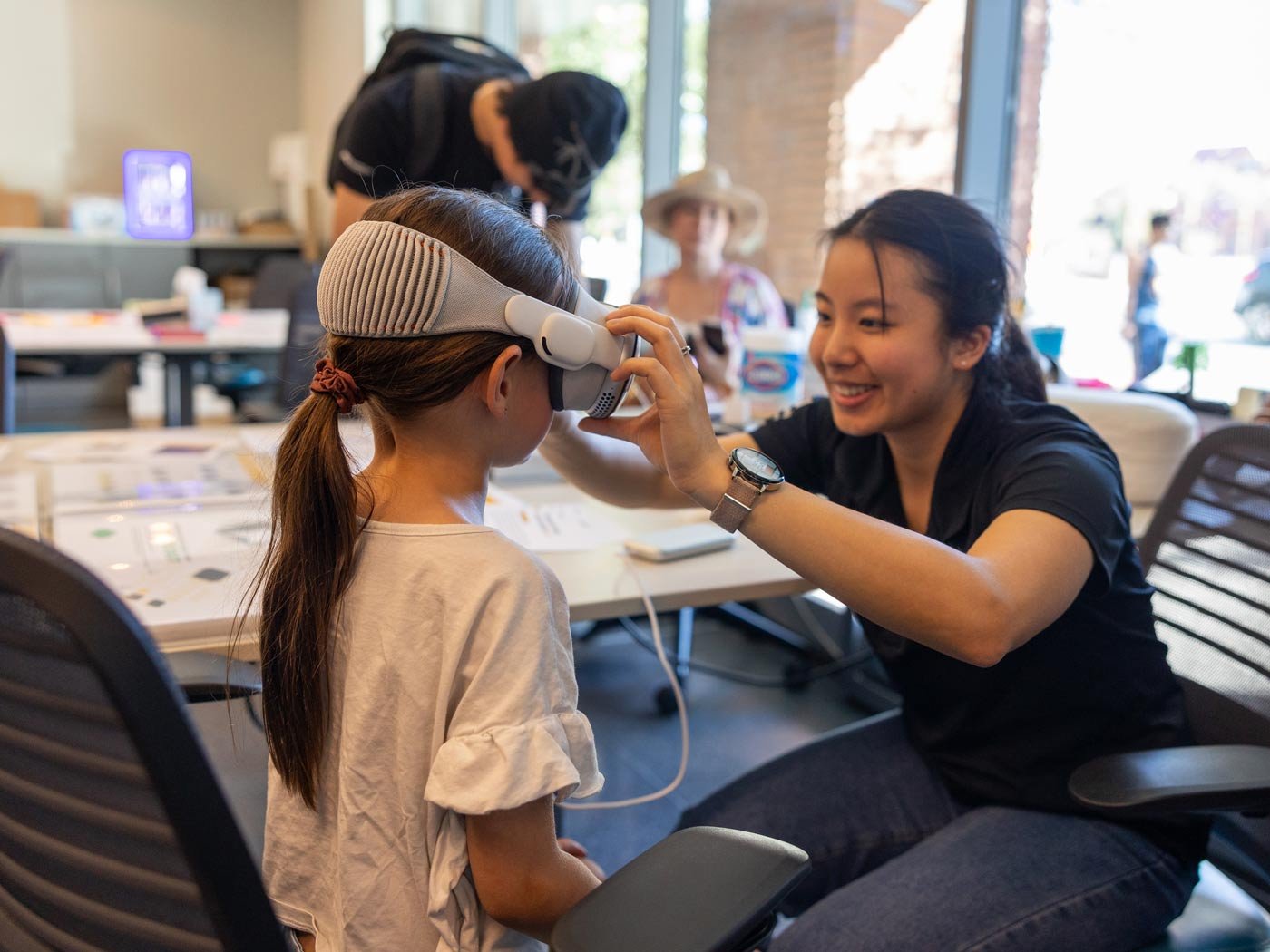 An ASU student fits a VR headset on a young girl during community outreach in ASU's Exploratory Social and Behavioral Sciences program.