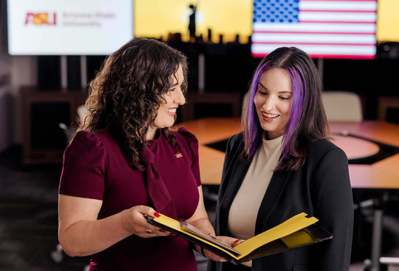 Two professionals review documents with an American flag behind them, reflecting civic perspectives in ASU's American Studies minor.
