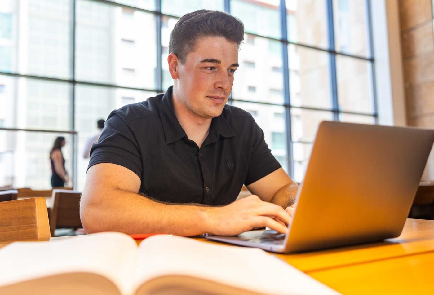A student studies independently with a laptop and books, reflecting critical inquiry in ASU's Applied Ethics minor.