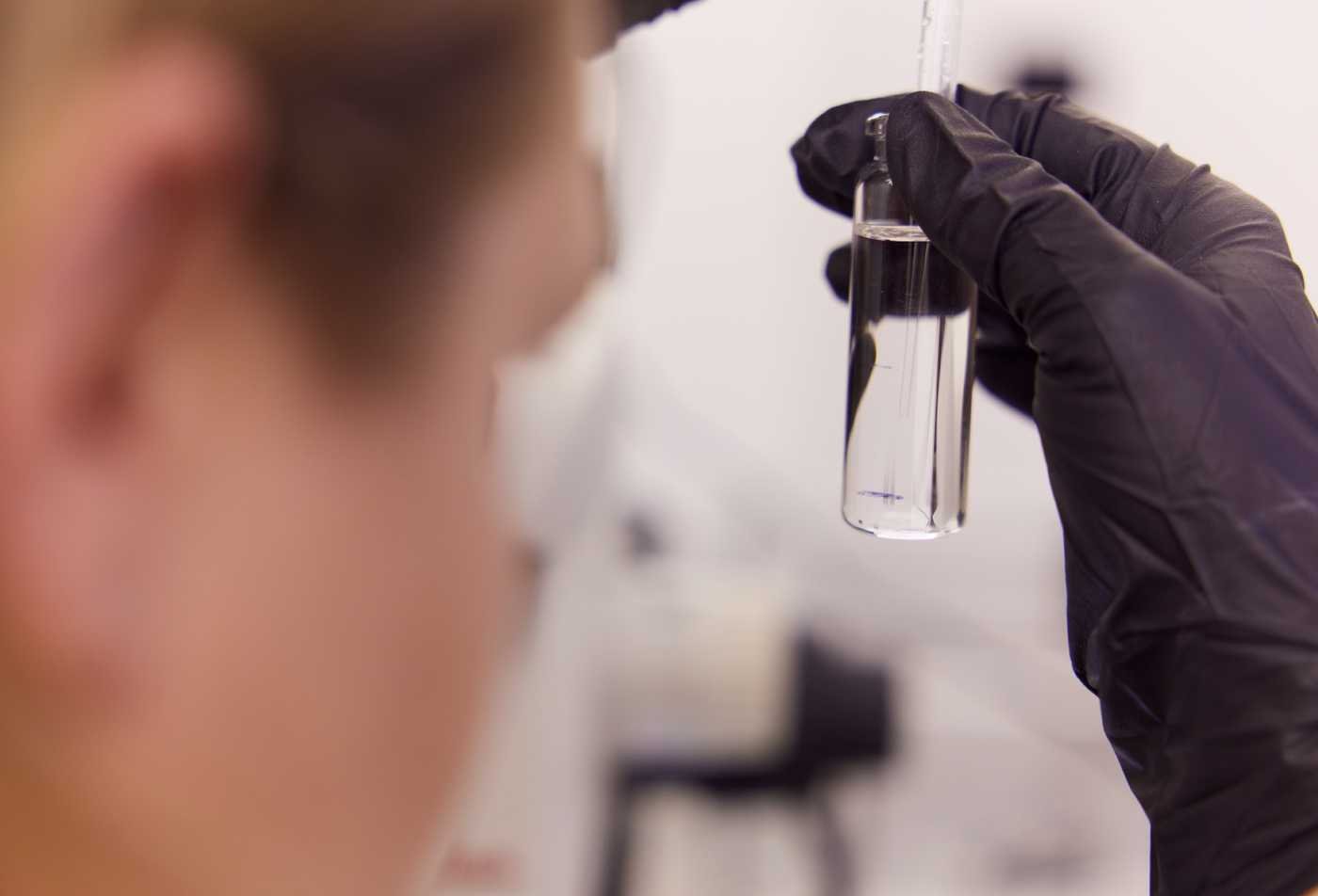 A researcher examines a liquid sample in a laboratory, demonstrating experimental analysis in ASU's Chemistry minor.