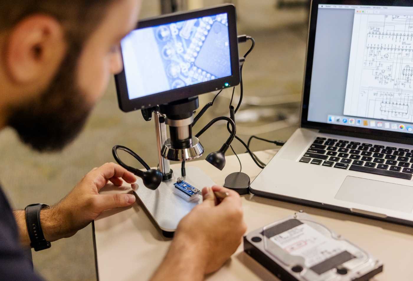 A technician examines electronic components with a digital microscope, demonstrating investigation in ASU's Digital Forensics, BS program.
