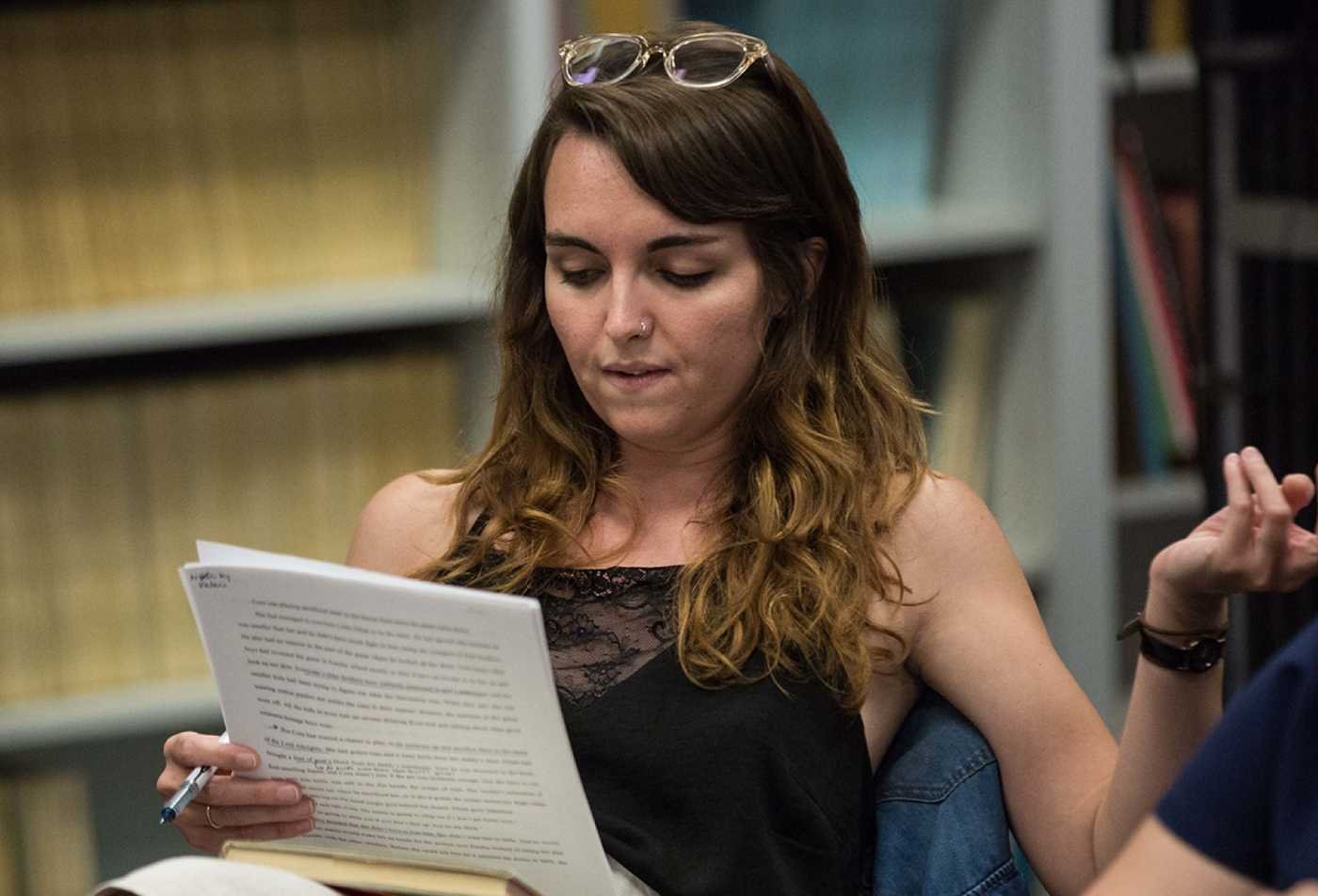 A student reviews written material in a library, reflecting literary analysis and discussion in ASU's English, BA program.