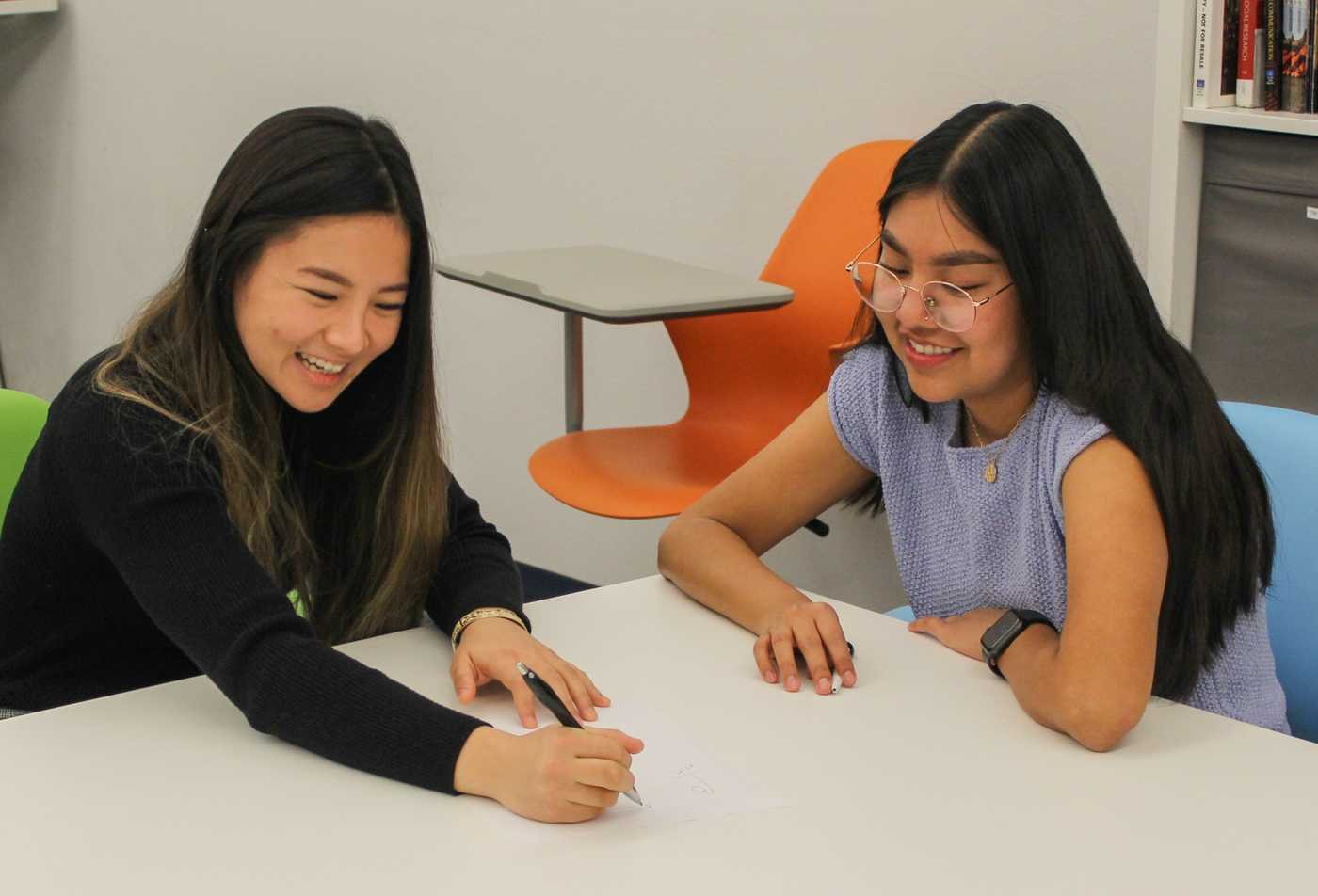 Two students share ideas at a table, highlighting interpersonal connections in ASU's Family Communication certificate.