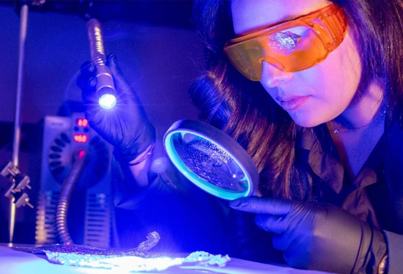 A researcher examines evidence under ultraviolet light, highlighting investigative techniques in ASU's Forensic Science minor.