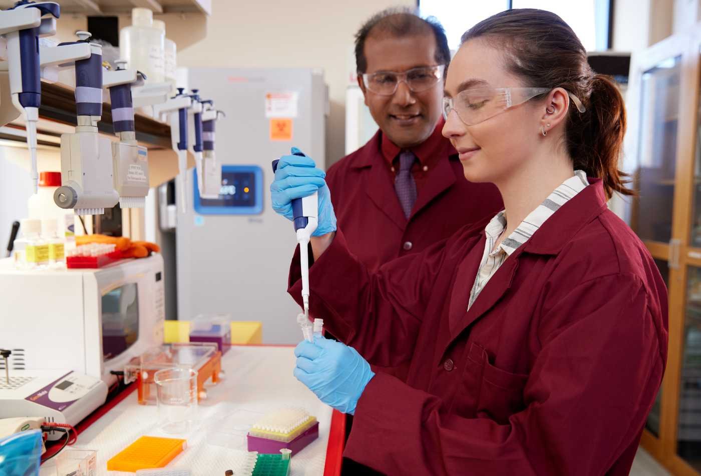 A researcher performs pipette work with faculty guidance, highlighting applied analysis in ASU's Forensic Science, MS program.