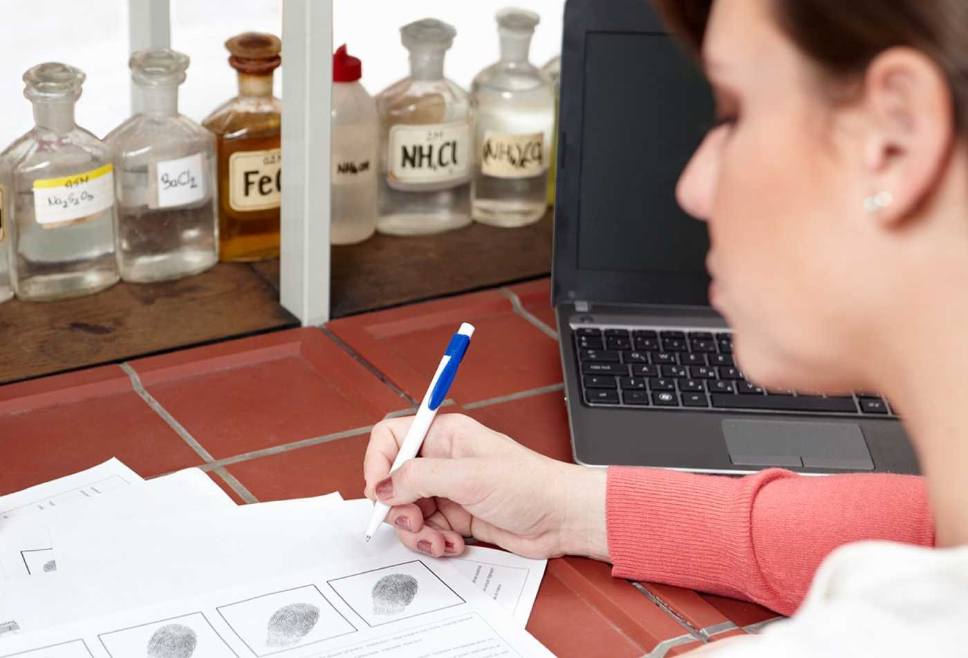 A student examines fingerprint records beside lab materials, highlighting skills gained in ASU's Human Factors in Forensic Science (Graduate Certificate).