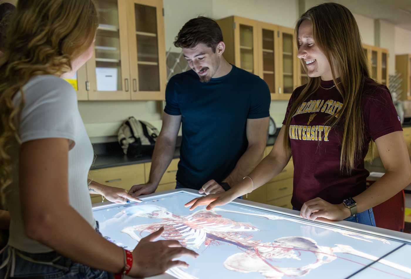 Students explore a digital anatomy table, demonstrating innovative learning in ASU's Exploratory Health and Life Sciences program.