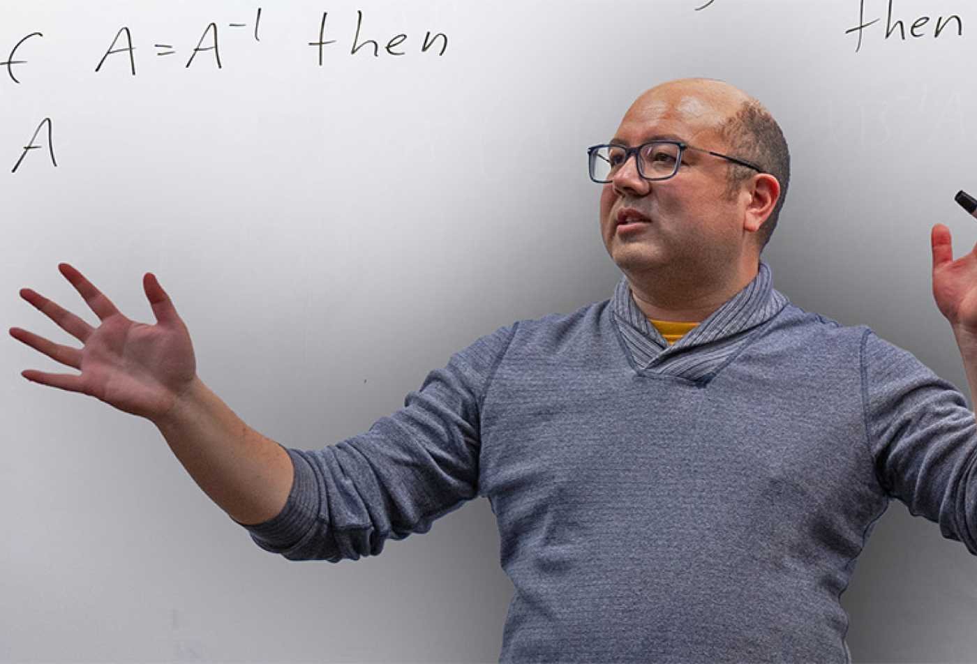 An instructor explains equations on a whiteboard, demonstrating analytical reasoning in ASU's Mathematics minor.