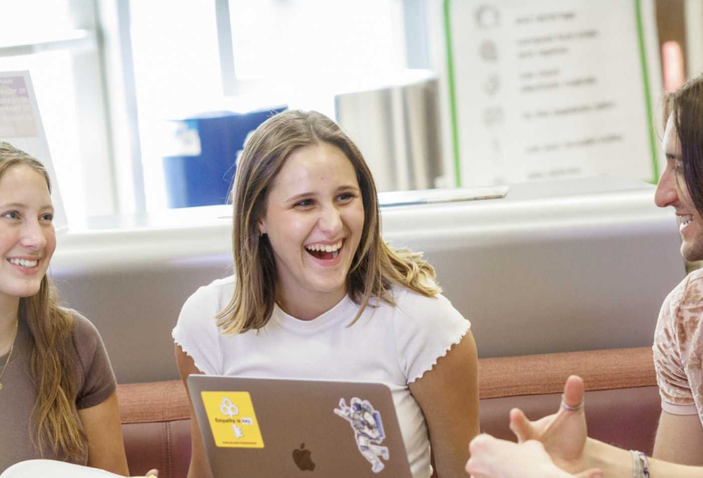 Students share ideas around a laptop, reflecting collaborative behavioral research in ASU's Psychology, MS program.