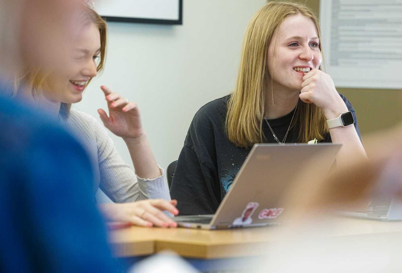 Students discuss ideas around a laptop, exploring well-being in ASU's Psychology (Positive Psychology), MS program.