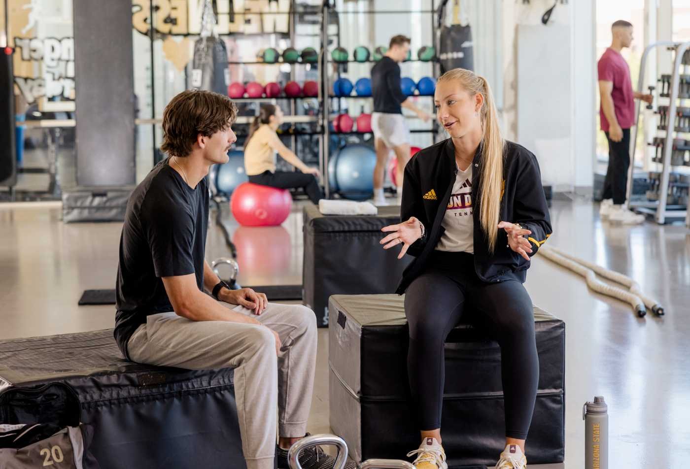 A student and mentor talk in a training facility, connecting mind and performance in ASU's Psychology (Sport Psychology), MS program.