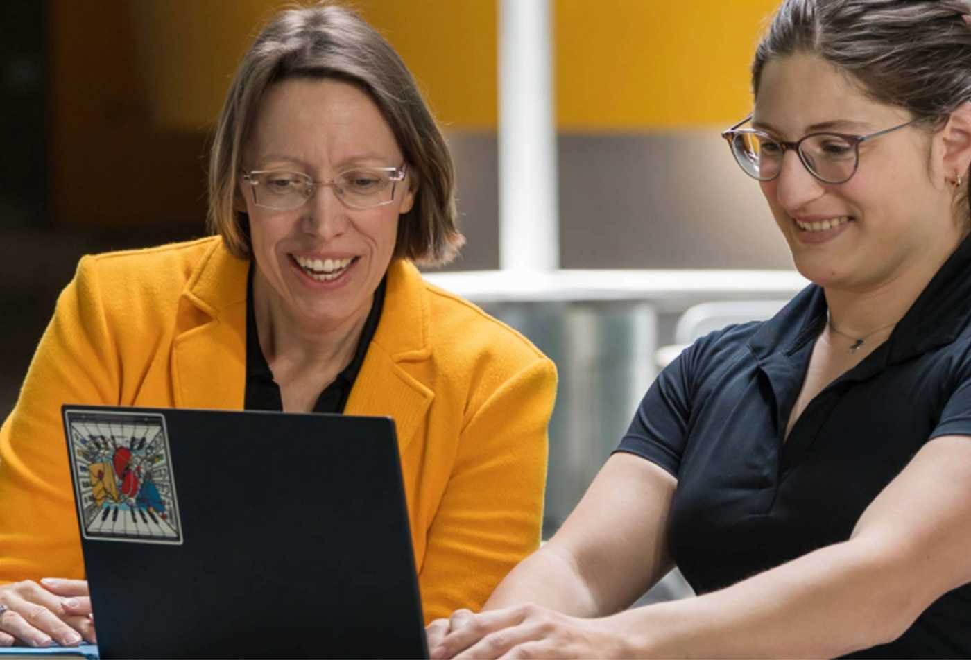 Faculty and students review data on a laptop, highlighting data-driven behavioral research in ASU's Psychology (Data Science), MS program.